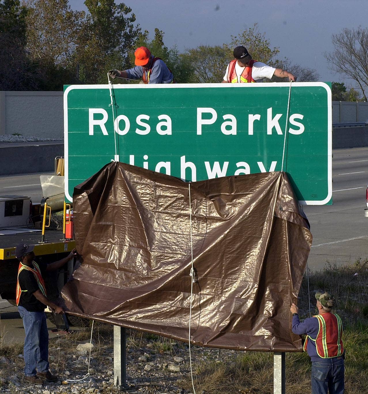 Workers with the Missouri Department of Transportation unveiled a new sign honoring civil rights activist Rosa Parks on Nov. 2, 2000, on Highway 55 in south St. Louis County. The one-mile stretch of highway honoring Parks is the same road where the Ku Klux Klan posted signs last year for adopt-a-highway. <em>Bill Greenblatt/Getty Images</em>