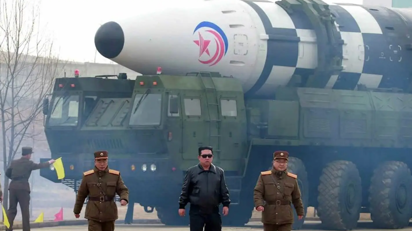 North Korean leader Kim Jong Un, in the black leather jacket and sunglasses at center, walks in front of a Hwasong-17 intercontinental ballistic missile on its transporter erector launch prior to the test on March 24, 2022.&nbsp;<em>North Korean state media</em>