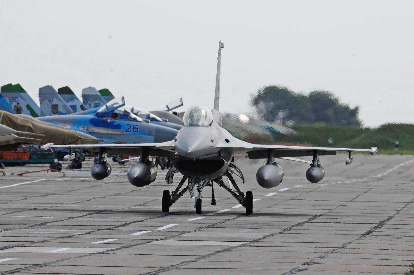 A U.S. Air Force F-16C taxis in front of Ukrainian Su-27 and MiG-29 fighter jets, on the ramp at Mirgorod Air Base, Ukraine. The Viper was in Ukraine for Exercise Safe Skies 2011. <em>U.S. Air Force</em>