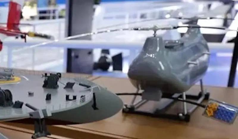 A model of a tandem-rotor drone seen on display at the Zhuhai Airshow in 2021. The model of the catamaran drone carrier, a portion of which is seen here on the left, was depicted carrying five of these uncrewed helicopters. <em>Chinese internet</em>