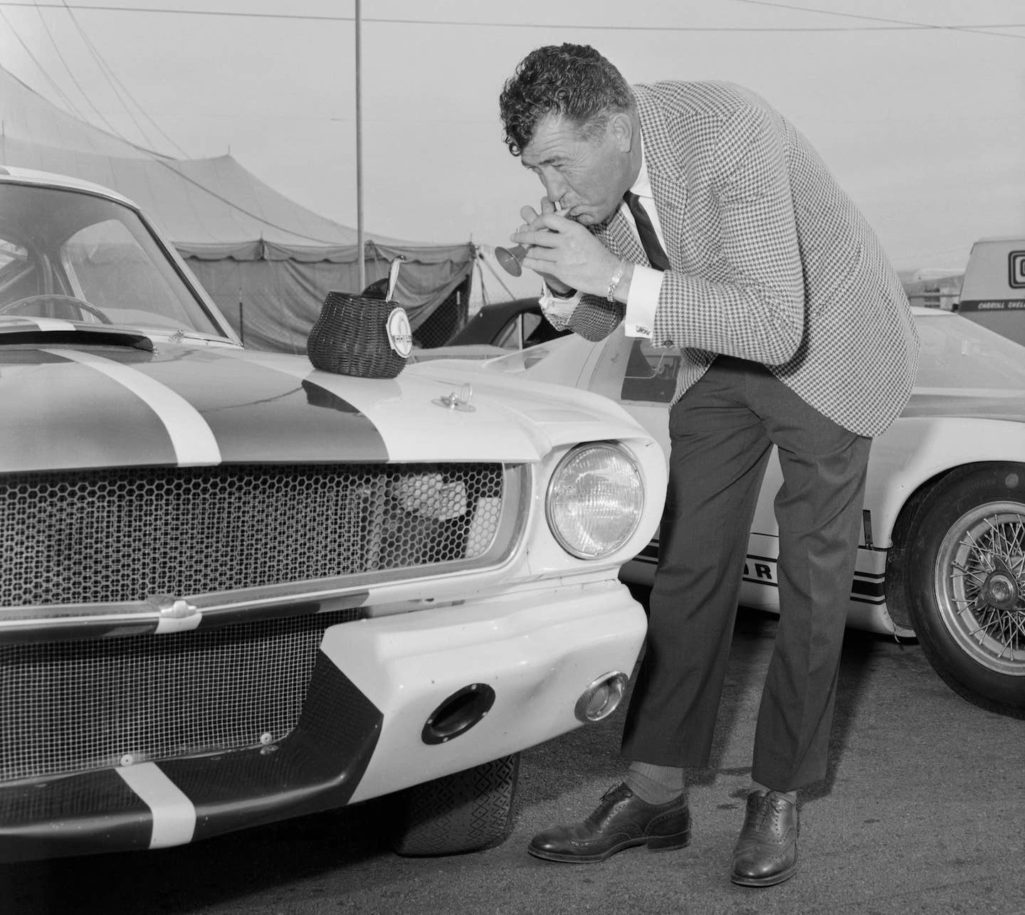 Carroll Shelby plays a toy flute to charm a toy Cobra out of its basket on the hood of a Ford Mustang Shelby GT350. <em>Getty Images</em>