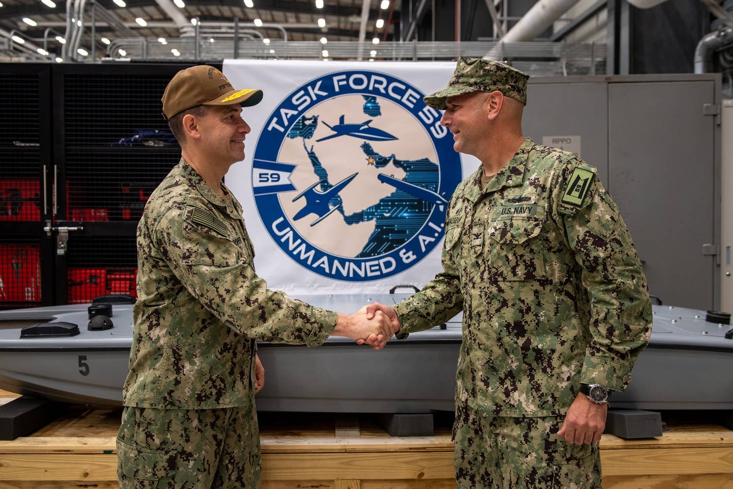 Vice Adm. Brad Cooper, left, commander of NAVCENT, U.S. 5th Fleet and Combined Maritime Forces, shakes hands with Capt. Michael D. Brasseur, commodore of Task Force during a commissioning ceremony for the unit. <em>Credit: U.S. Navy photo by Mass Communication Specialist 2nd Class Dawson Roth</em>