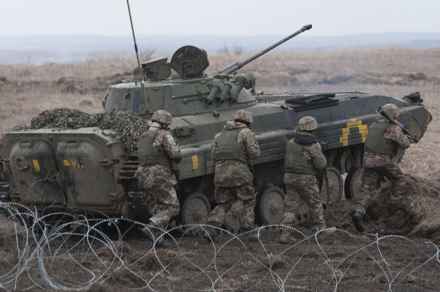 Ukrainian soldiers rush through a wire obstacle while taking cover behind their BMP-2 armored vehicle during a live-fire training exercise in 2017.<em> U.S. Army</em><a href="https://api.army.mil/e2/c/images/2017/03/18/470333/original.jpg" target="_blank" rel="noreferrer noopener"></a>