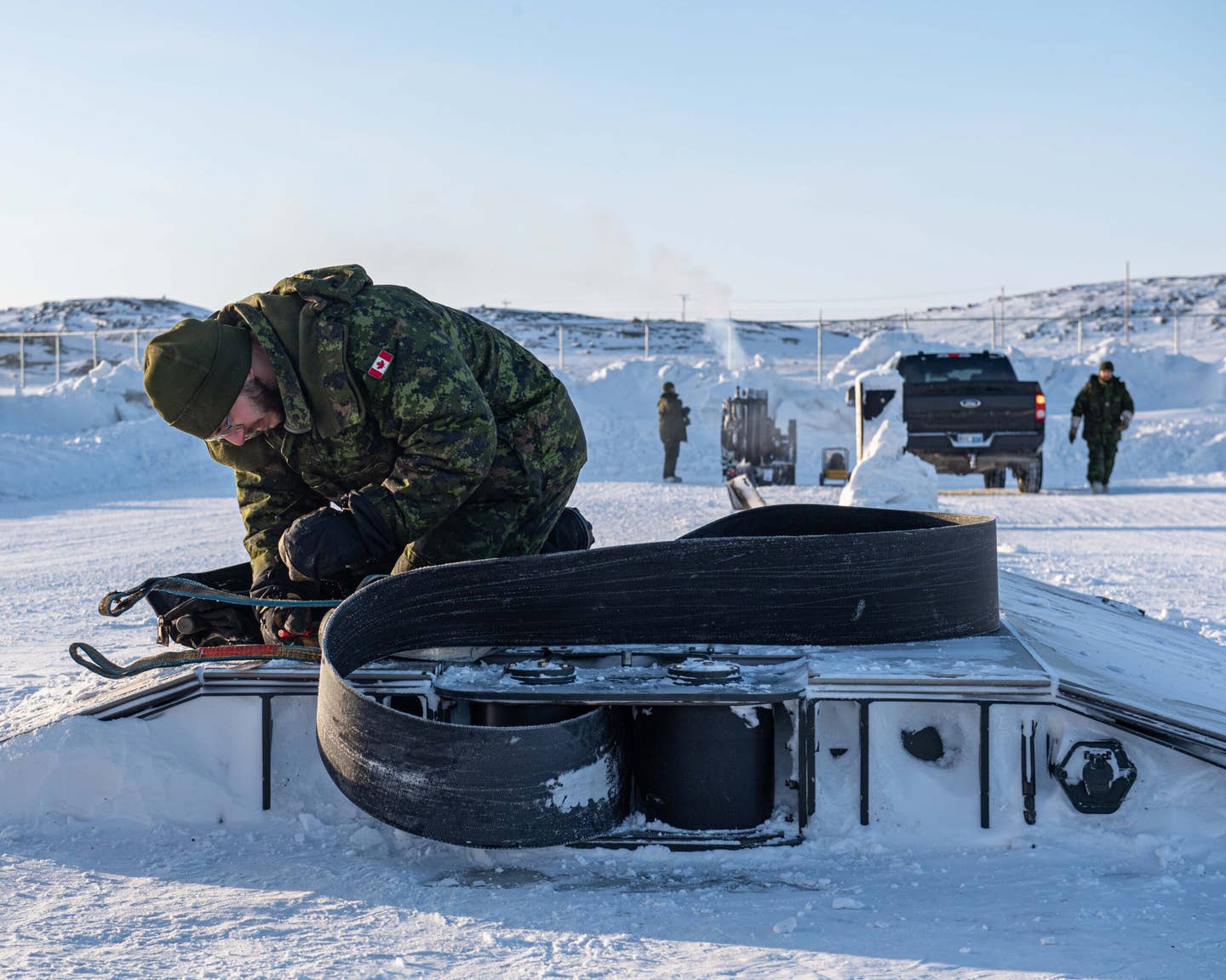 Canadian Corporal Jeff Gonthier of the Fix Aircraft Arresting System (FAAS) prepares the arrestor cable before Royal Canadian Air Force CF-18 Hornet operations at Iqaluit during Operation Noble Defender, Jan. 27, 2023. <em>Canadian NORAD Region Public Affairs</em>