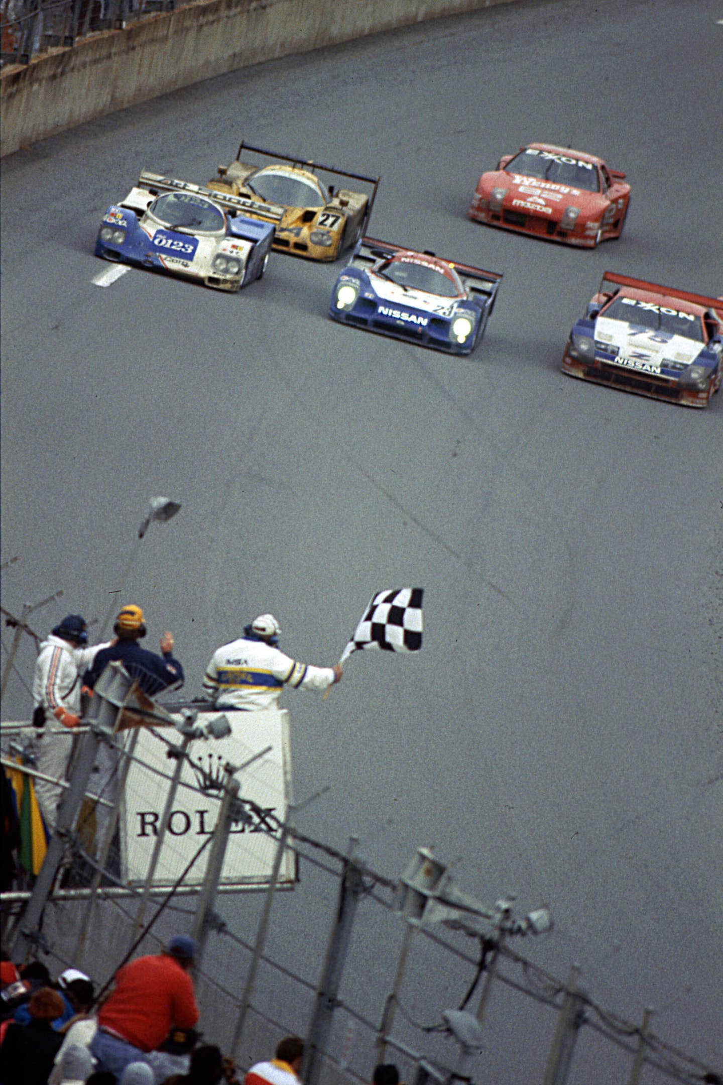 DAYTONA BEACH, FL — February 2, 1992:  At Daytona International Speedway, the winning Nissan R91-CP is sandwiched between two other competitors as the checkered flag falls to end the Rolex 24 at Daytona.  Masahiro Hasemi, Kazuyoshi Hoshino and Toshio Suzuki took the victory racing for Nissan Motorsports of Japan.  (Photo by ISC Images and Archives via Getty Images)