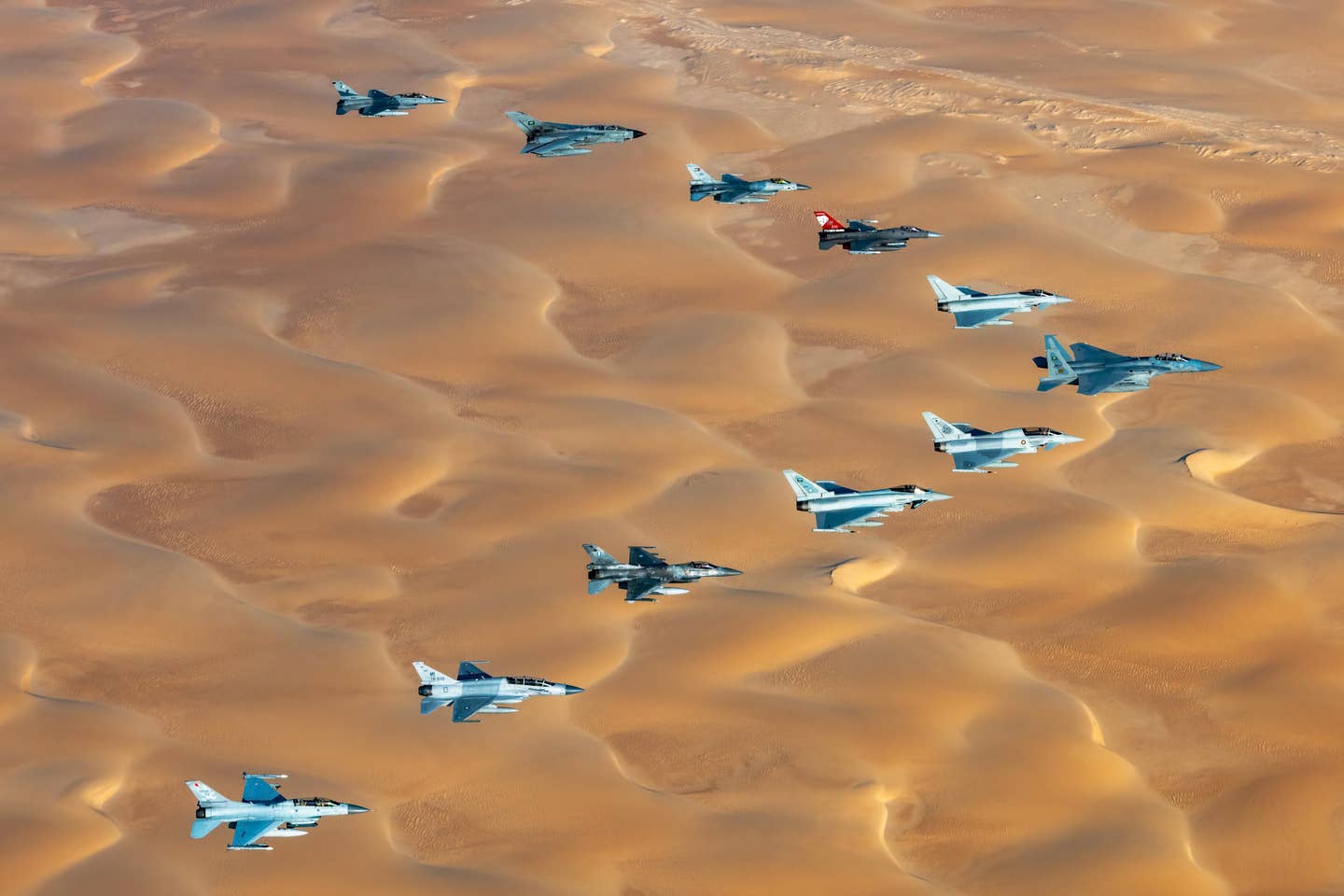 An interesting reflection of the current international fighter jet scene in a single picture from the recent Spears of Victory 2023 exercise in Saudi Arabia. Seen here are F-16s and Eurofighter Typhoons from a number of countries, as well as a Saudi F-15 Eagle in the lead and, second from the top, one of that country's aging Panavia Tornado swing-wing combat jets. One of Pakistan's Chinese-made two-seat JF-17B combat jets is seen second from the bottom. <em>Government of Saudi Arabia</em>