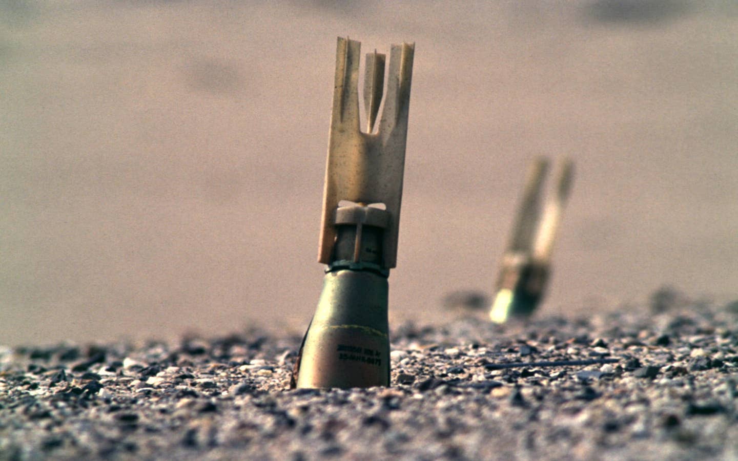 Unexploded Mk 118 bomblets embedded in a tarmac road in north-eastern Kuwait March 1991. <em>Credit: Johnny Saunderson/Wikimedia Commons</em>
