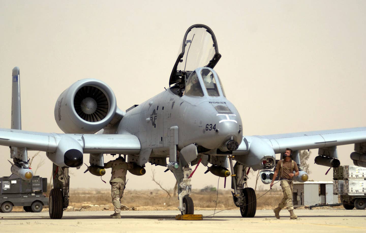 Crew chiefs with the 392nd Air Expeditionary Wing conduct pre-flight checks on an A-10 at a forward-deployed location supporting Operation Iraqi Freedom, in March 2003. This jet carries a mixture of unguided bombs, AGM-65 Mavericks, and a pod for unguided rockets. <em>U.S. Air Force photo by Staff Sgt. Shane A. Cuomo</em>