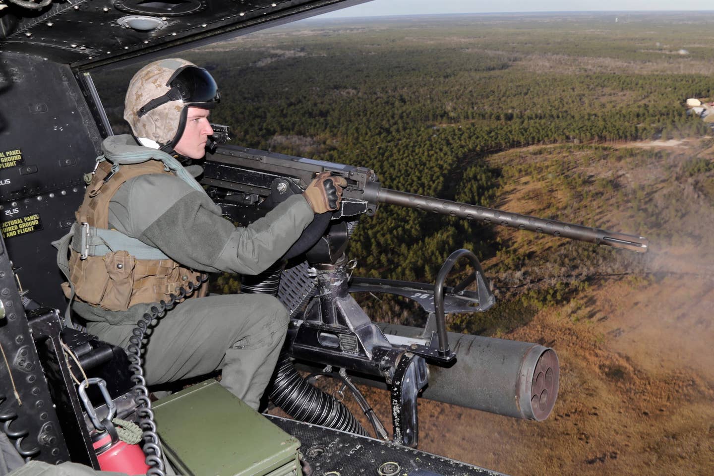 A UH-1Y crewman fires the big .50 caliber door gun. (Author)