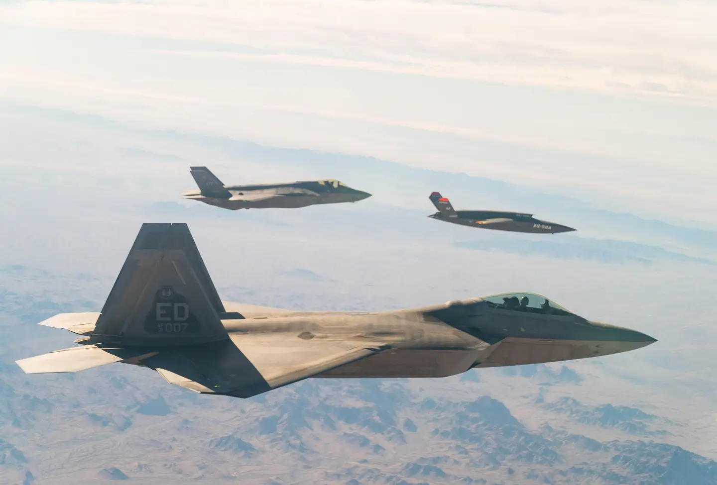 A U.S. Air Force F-22 Raptor and F-35A Lightning II fly in formation with the XQ-58A Valkyrie over the U.S. Army Yuma Proving Ground testing range, Ariz., during a series of tests on Dec. 9, 2020.&nbsp;<em>Credit: U.S. Air Force photo by Tech. Sgt. James Cason</em>