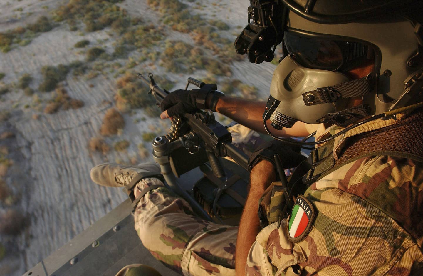 An Italian Air Force gunner aboard an HH-3F helicopter flying near its base of Camp Mittica, in Nasiriyah in southern Iraq, in October 2004. <em>Photo by Marco Di Lauro/Getty Images</em>