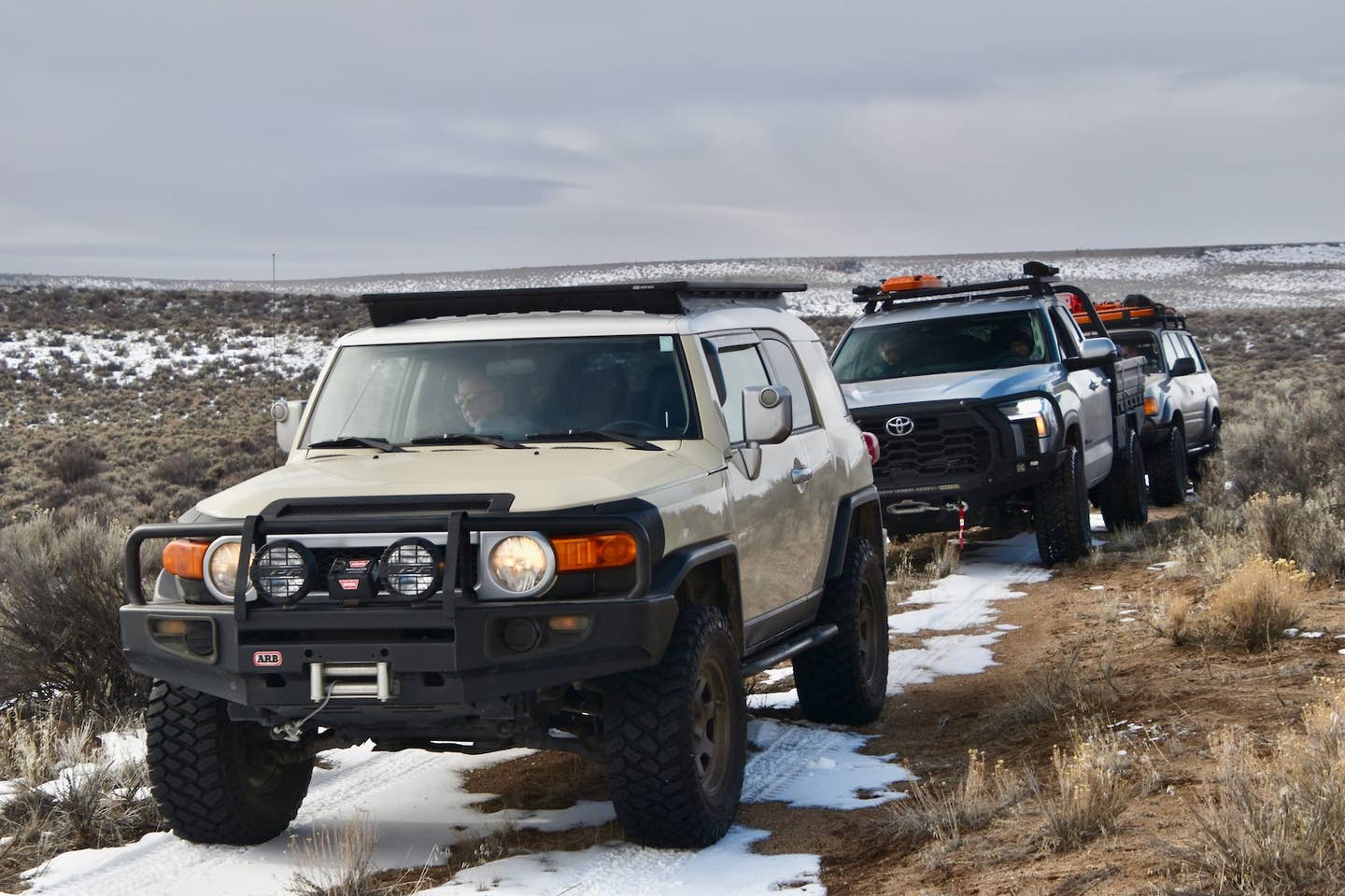 A Toyota FJ Cruiser leads a Tundra and Land Cruiser (80-series) down a trail