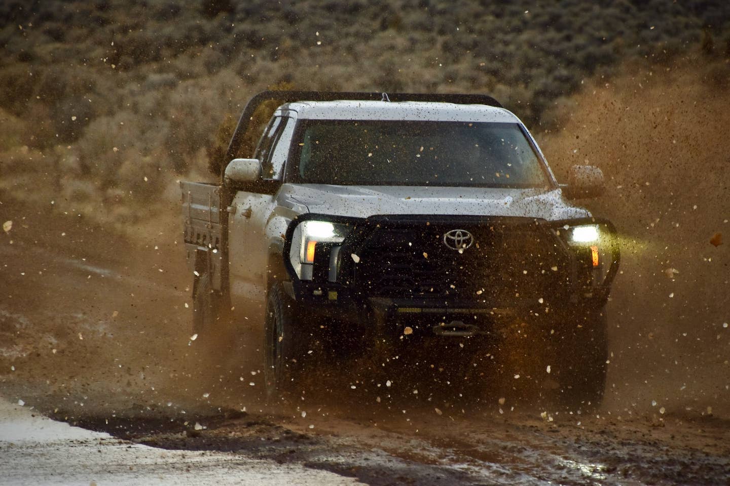 A Toyota Tundra splashes through mud at high speed