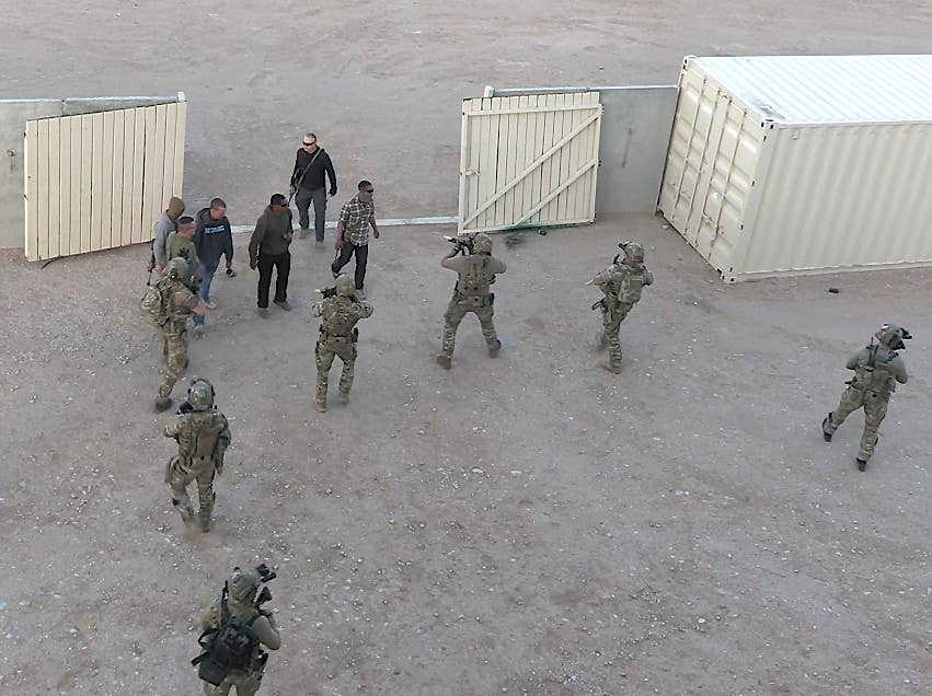 SEALs push the mock militants out of the compound during the consulate evacuation training exercise. One of them, at bottom left, appears to have a collapsible stretcher on their back. The individual carrying the system with antennas is seen at right. <em>USMC capture</em>