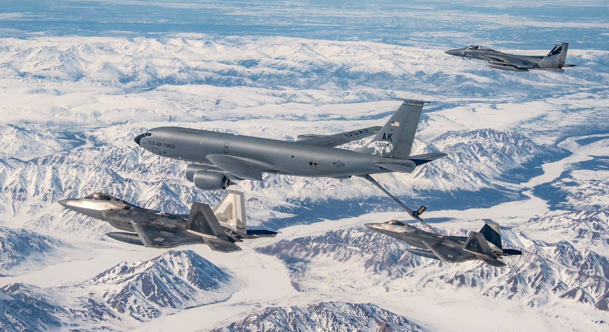 A pair of F-22s, one of which is seen refueling from a KC-135 tanker, fly with an F-15C over Alaska. <em>USAF</em>