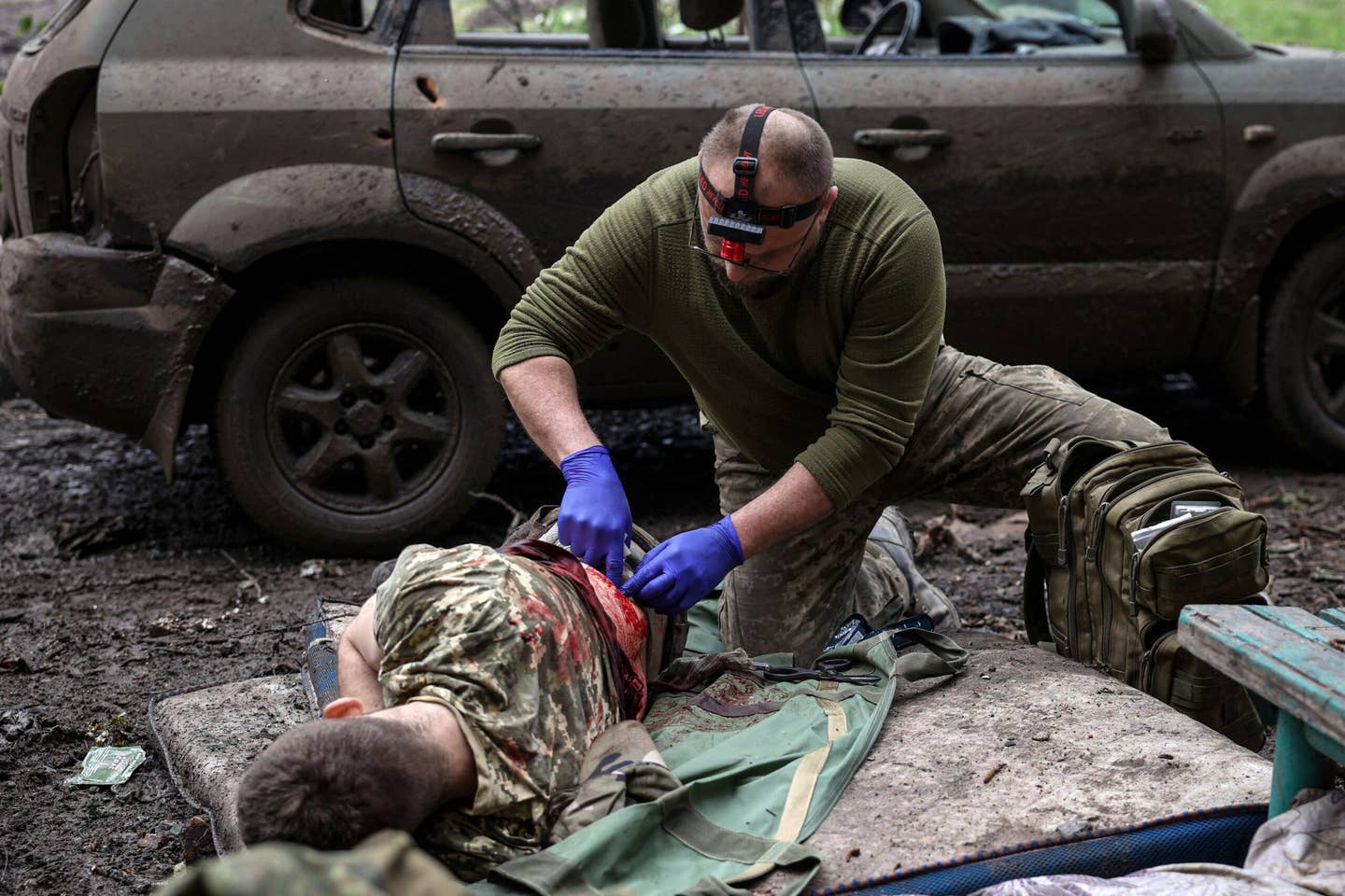 A military paramedic treats a Ukrainian injured serviceman on a street in the frontline city of Bakhmut. (Photo by ANATOLII STEPANOV/AFP via Getty Images)