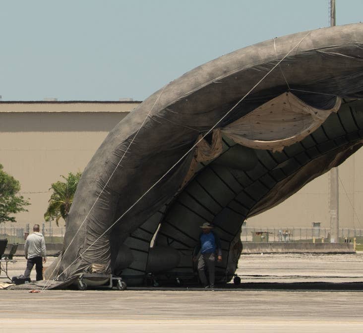 A close-up of one side of the deception hangar shows what appears to be at least a partially inflatable structure, the wheeled frame at the bottom, and the tarp-like covering. <em>Air National Guard</em>