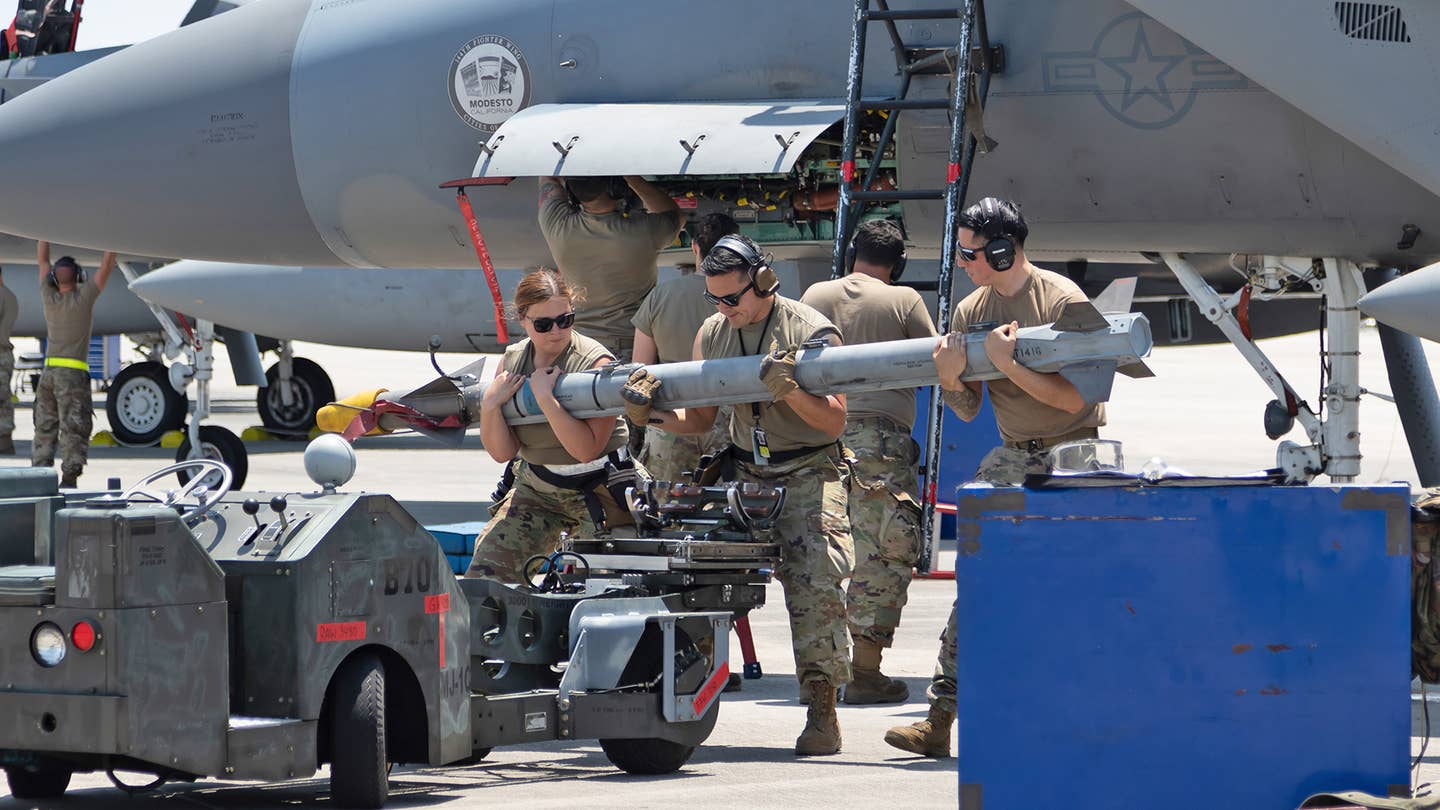 Maintainers lug an AIM-9X Sidewinder for loading onto an F-15. <em>Richard Collens</em>