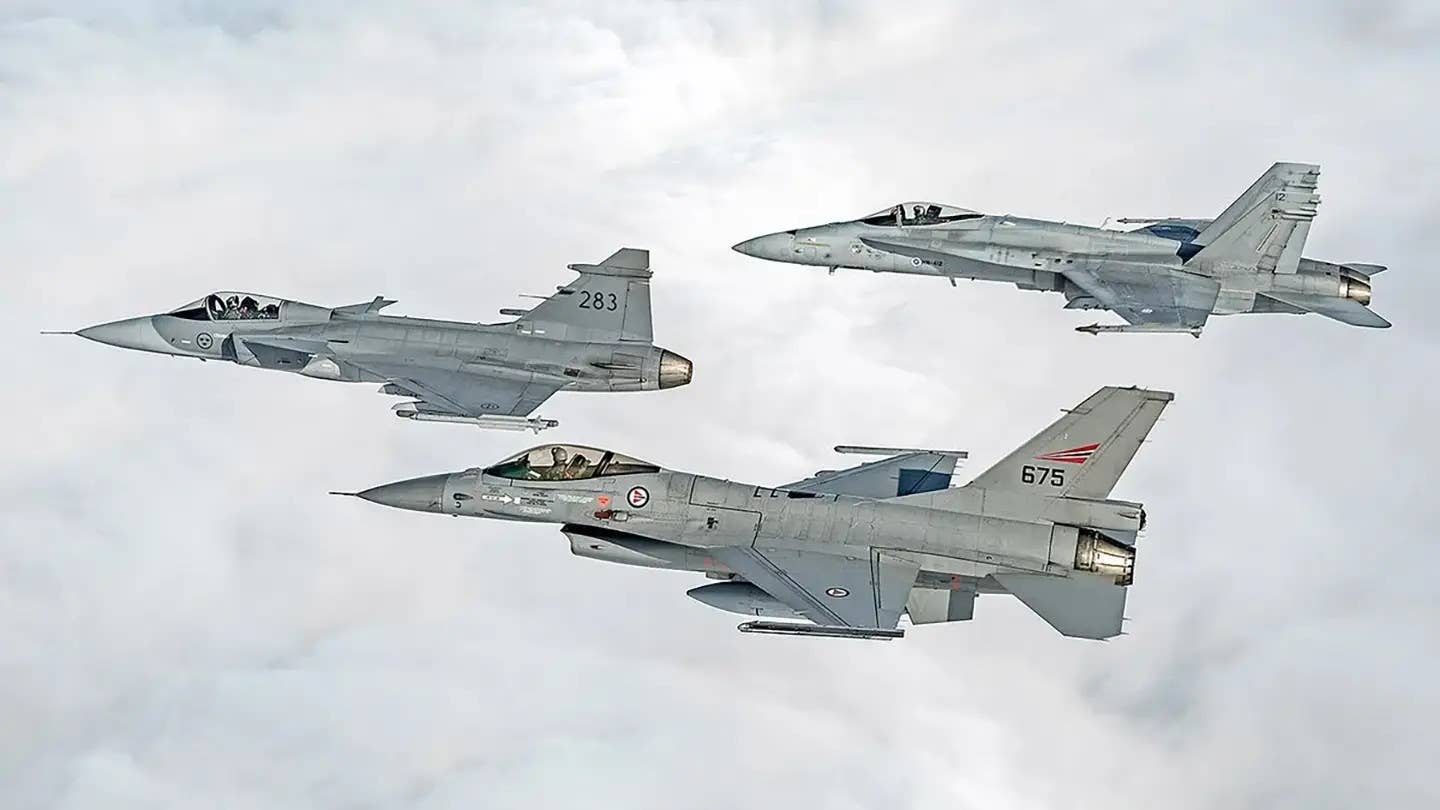 A Swedish Gripen C, at left, flies together with a Norwegian F-16 Viper, at bottom right, and a Finnish F/A-18 Hornet, at top right. <em>Finnish Air Force</em>