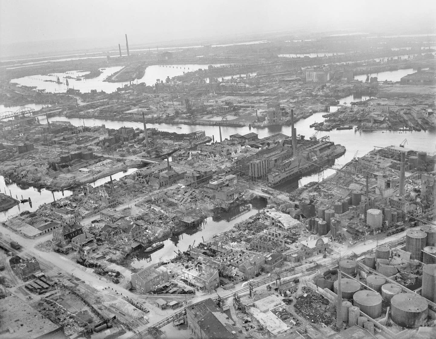An oblique aerial view of severely damaged docks in the Steinwerder district of Hamburg, looking southwest from over the Rive Elbe. The area was subjected to repeated attacks by Bomber Command and USAAF raids. <em>Crown Copyright</em>