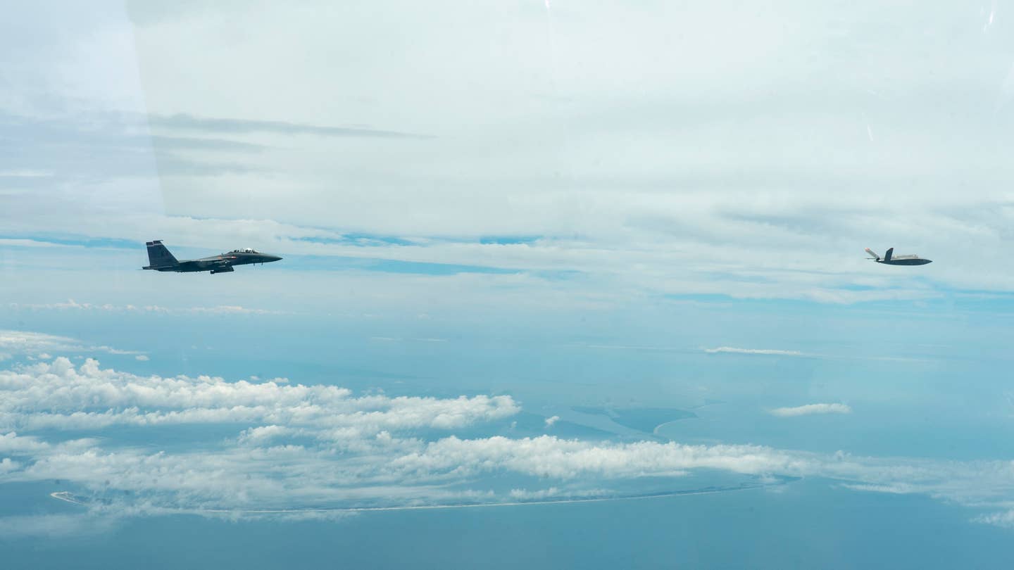 An XQ-58A Valkyrie drone, at right, flies in the Eglin Test and Training Complex together with an Air Force F-15E Strike Eagle during the July 25, 2023 test. <em>USAF</em>