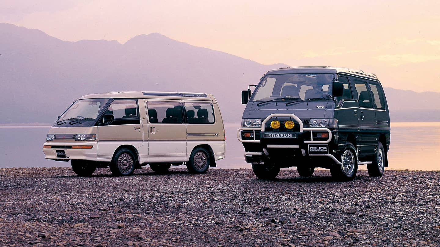 Mitsubishi Delicas on the shore of a lake with a mountain backdrop