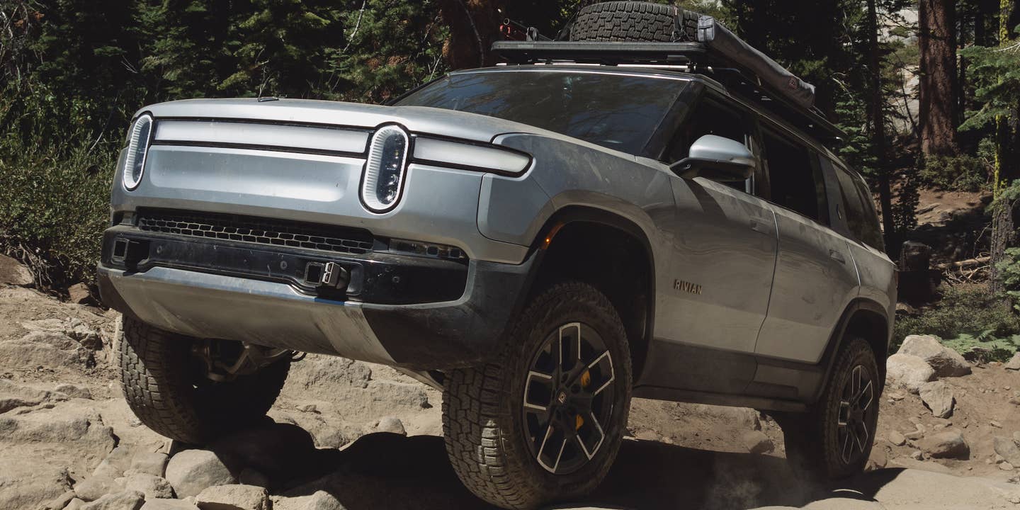 Rivian R1S SUV in silver, driving uphill on a trail