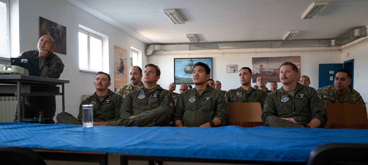 U.S. Air Force airmen assigned to the 435th Contingency Response Squadron and 31st Fighter Wing, receive a slideshow presentation from a Serbian Air Force airman assigned to the 119th Mixed Helicopter Squadron at Sgt./Pilot Mihajlo Petrovic Air Base, Serbia, Aug. 9, 2023. <em>U.S. Air Force photo by Airman 1st Class Edgar Grimaldo</em><br>