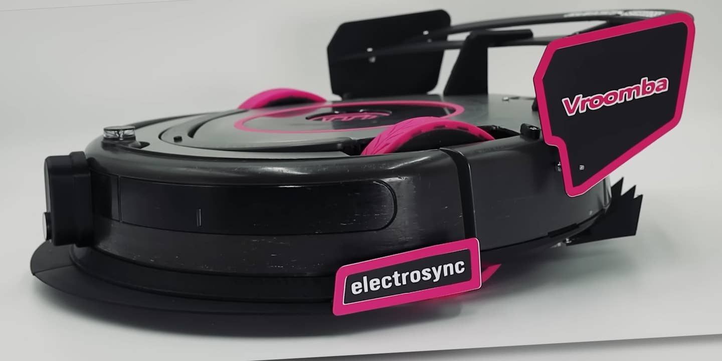 World's fastest Roomba robot vacuum cleaner. The Roomba has visible pink wheels and trim on its aerodynamic elements, including pink-rimmed front and rear wing end plates.
