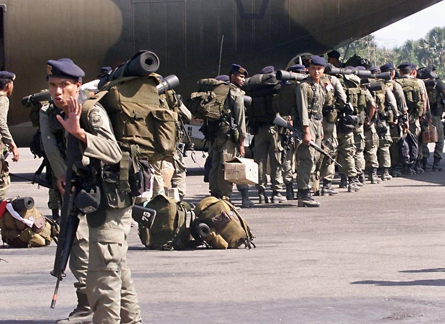 A member of the Indonesian Mobile Police Brigade tries to stop a photographer from taking pictures of his troops boarding an Indonesian Air Force transport plane at Dili Airport in October 1999. At the time, around 100 Indonesian troops were departing for Jakarta, as part of troop withdrawal after East Timor voted for independence from Indonesia.  <em>Photo by ROMEO GACAD/AFP via Getty Images</em>