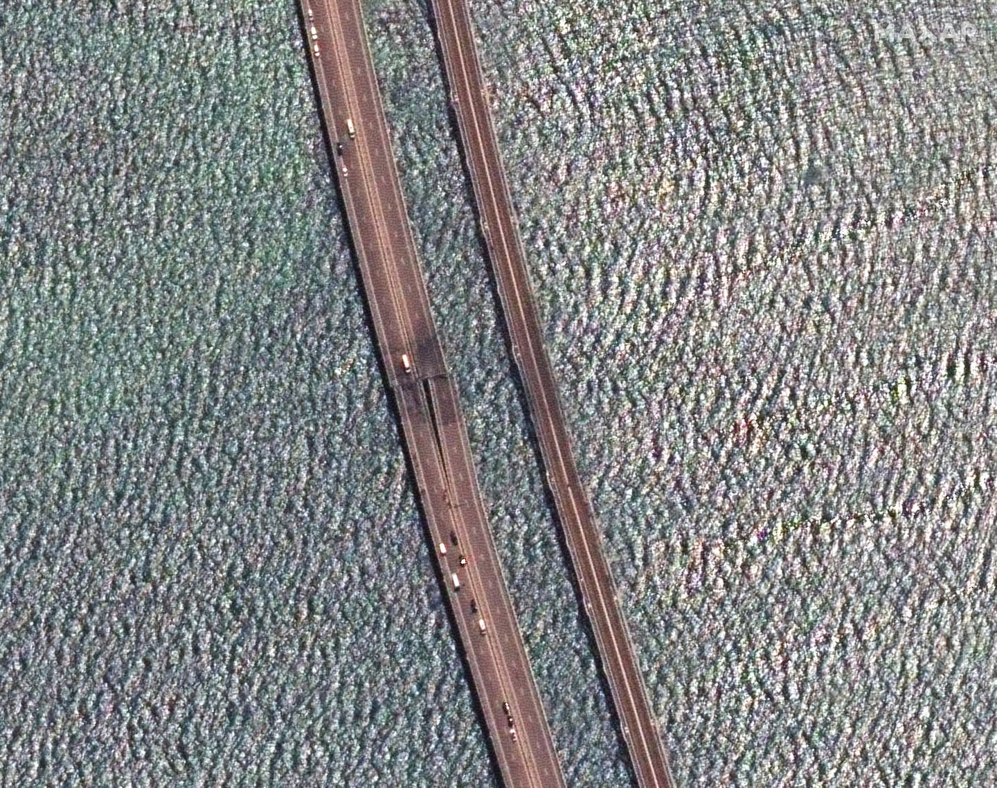 A close-up satellite image of the Kerch Bridge, damaged by a Ukrainian uncrewed surface vessel July 17. The rotated image shows the north span of the bridge on the left. (Satellite image ©2023 Maxar Technologies)