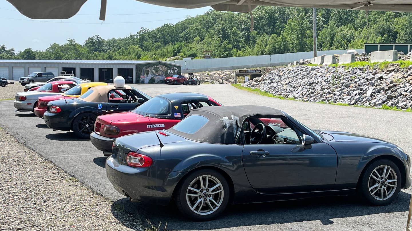 A range of Miatas used for track-driving instruction. In the background you can see rental garages people can hire for storage or wrenching sessions. <em>Andrew P. Collins</em>