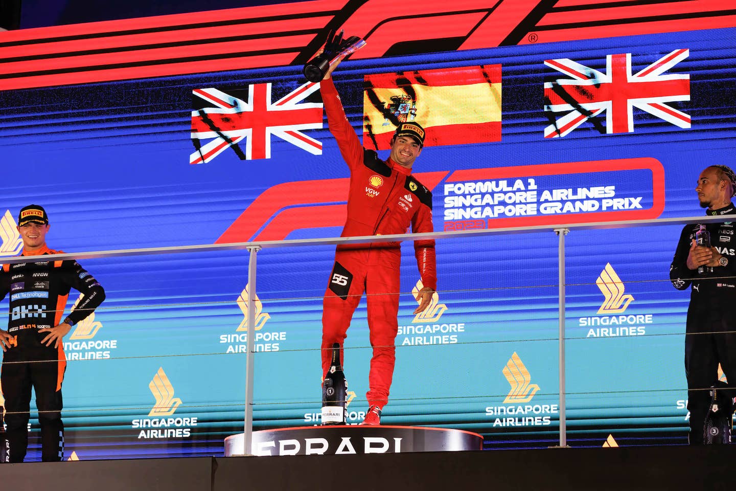 Singapore Formula 1 Grand Prix winner Carlos Sainz lifts his trophy on the top step of the podium.