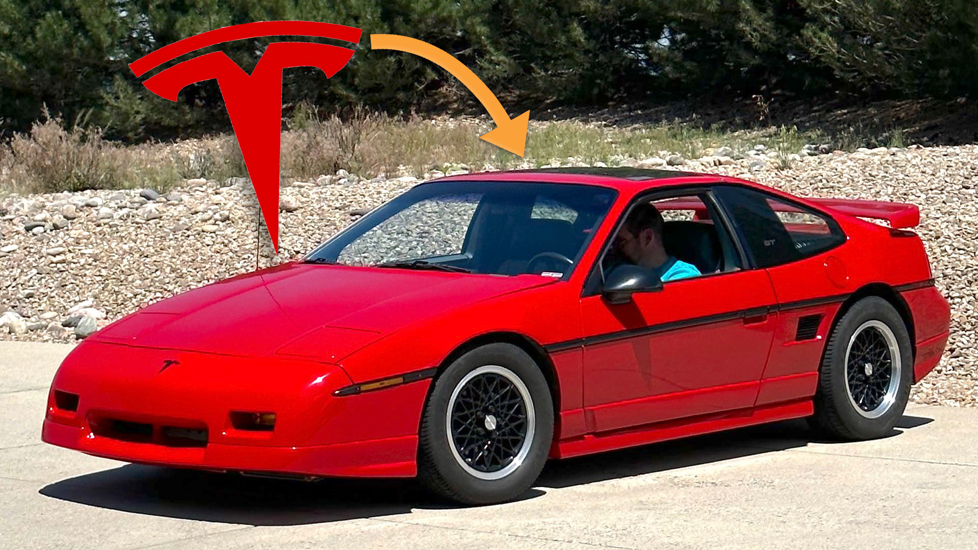A red Pontiac Fiero with a Tesla logo hovering above it