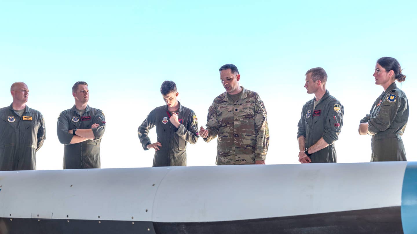 Another picture of Lt. Col. Jeffrey Komives, in the center in the camouflage uniform, as he provides an 'orientation' about the Hypersonic Attack Cruise Missile at Edwards Air Force Base yesterday. <em>USAF</em>