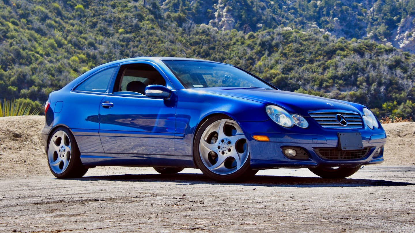 Blue Mercedes C320 Sportcoupe against a forested background
