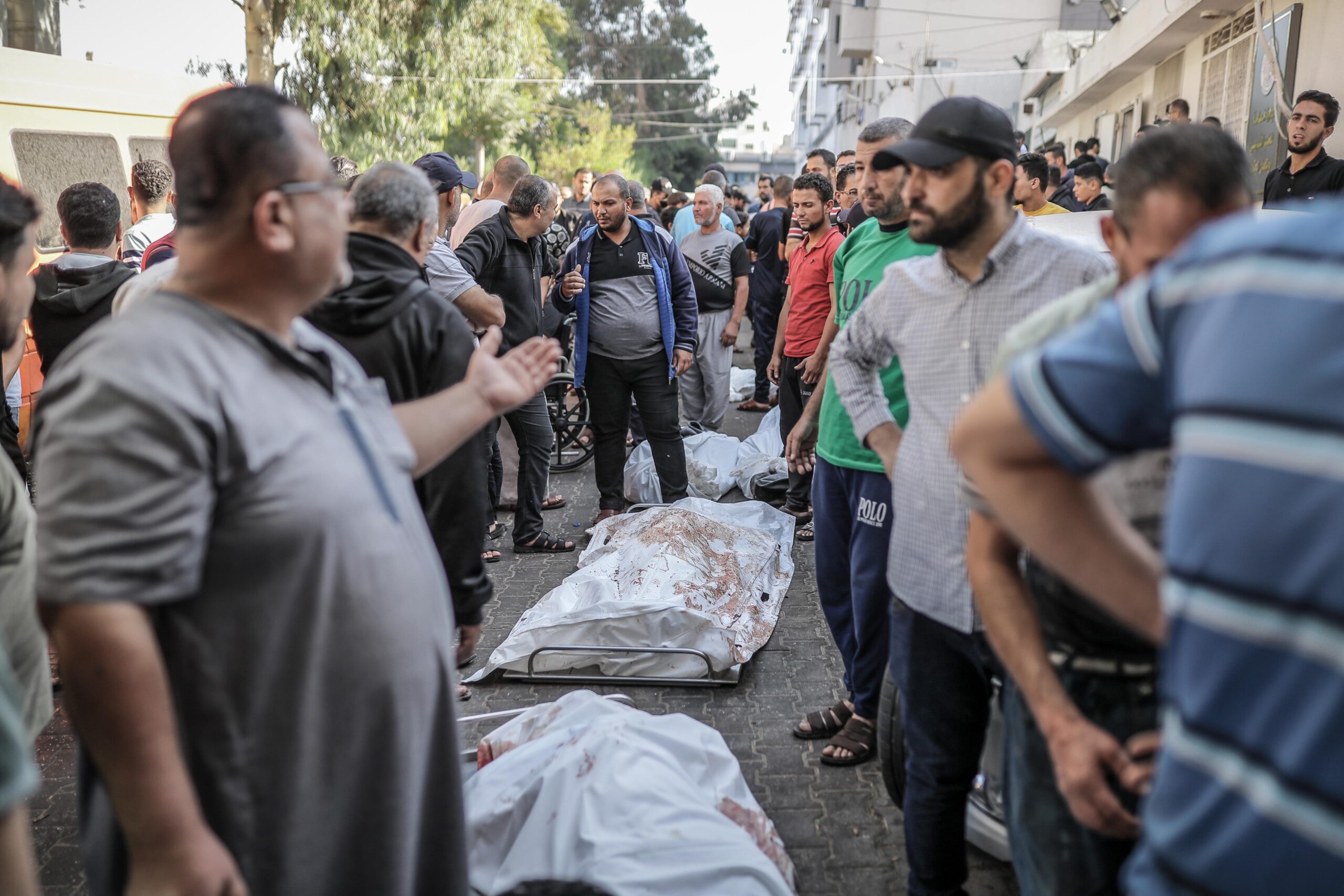 Citizens are seen next to the dead bodies of people who died in the attack on the Al-Ahli Baptist Hospital before being buried in Gaza City, Gaza on October 18, 2023. According to the Palestinian authorities, Israeli army is responsible for the deadly bombing while Israel blames an errant Palestinian Islamic Jihad rocket. (Photo by Belal Khaled/Anadolu via Getty Images)