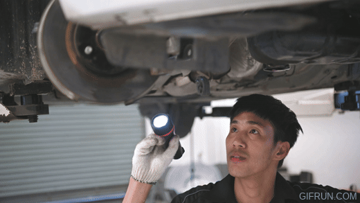 Mechanic inspecting the underside of a car