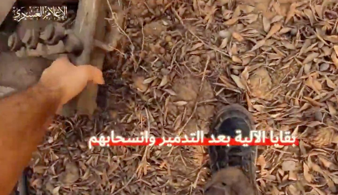 Een Hamas-strijder raapt een stuk metaal op, vermoedelijk na de aanval op de tank.