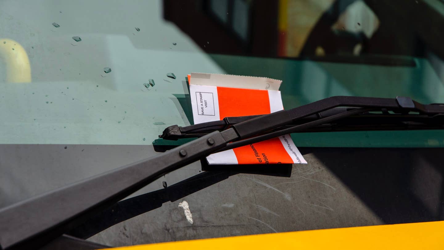 Close up of a parking ticket under a delivery truck windshield wiper.