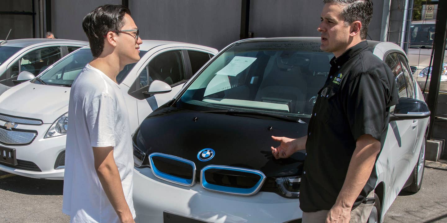 Mariano Avalos (R), owner of a car dealer that sells used electric cars imported from the United States, talks to a customer in San Jose on December 13, 2018. - Electric vehicles slowly gain space in Costa Rica's congested streets, a country that prides itself on being an ecological paradise and works on an agenda to decarbonize its economy. Despite the 600 electric cars in private hands seem like a drop of water in a vehicle fleet of around 1.4 million, experts foresee an exponential growth. (Photo by Ezequiel BECERRA / AFP) (Photo credit should read EZEQUIEL BECERRA/AFP via Getty Images)