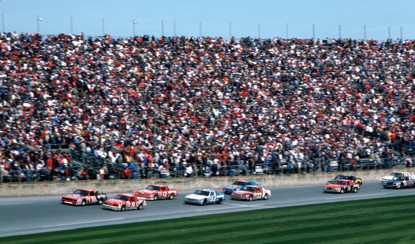 NASCAR fans pack the grandstands as a group of cars pass at the Daytona International Speedway during the 1986 Daytona 500 on February 16, 1986 in Daytona Beach, Florida. 