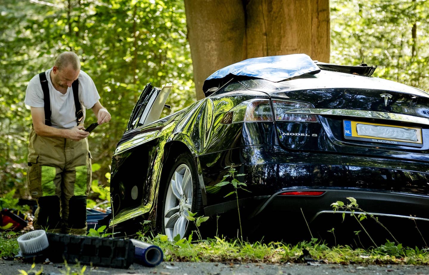 An emergency responder examines the wreckage of a fatal Tesla crash in The Netherlands