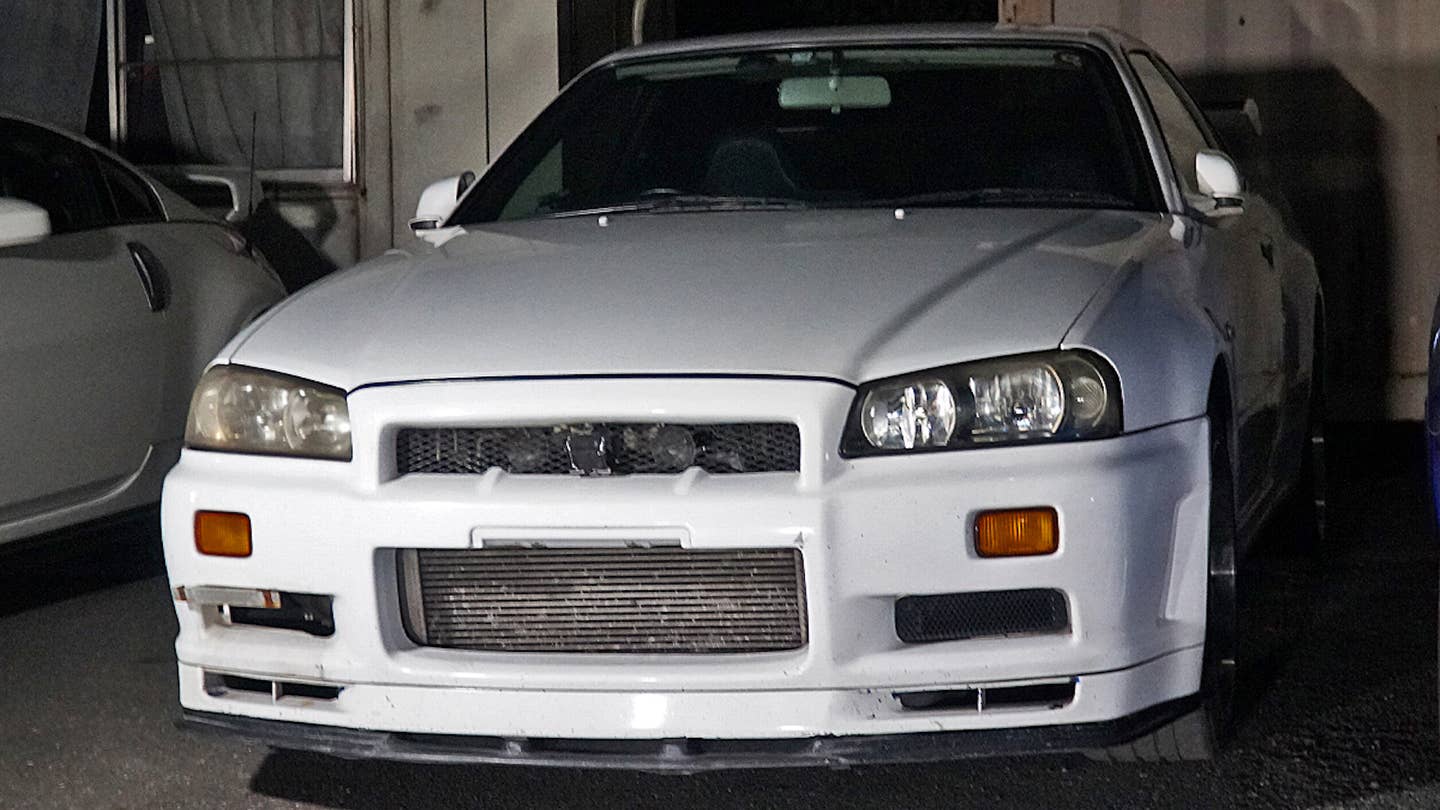 A white R34 Nissan Skyline GT-R in a dim shipping container