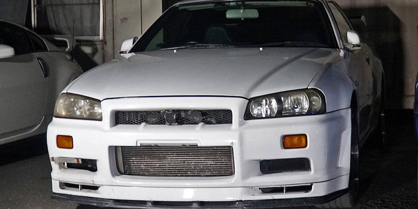 A white R34 Nissan Skyline GT-R in a dim shipping container