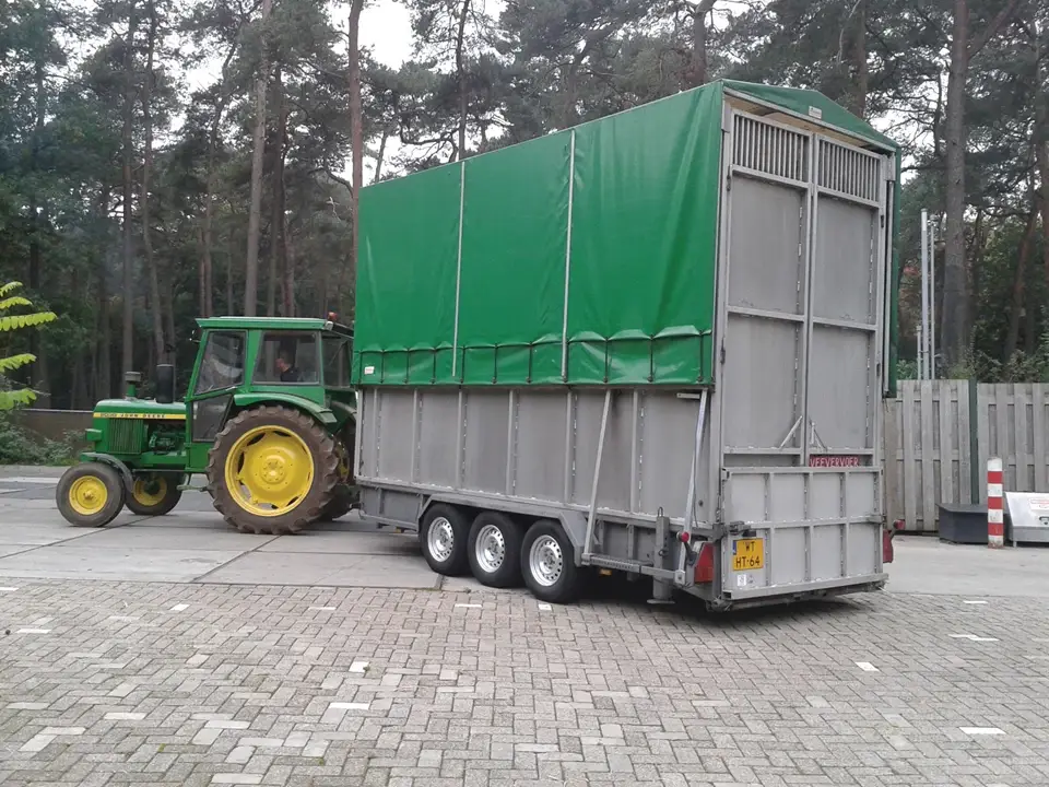 A tall, metal trailer towed by a tractor