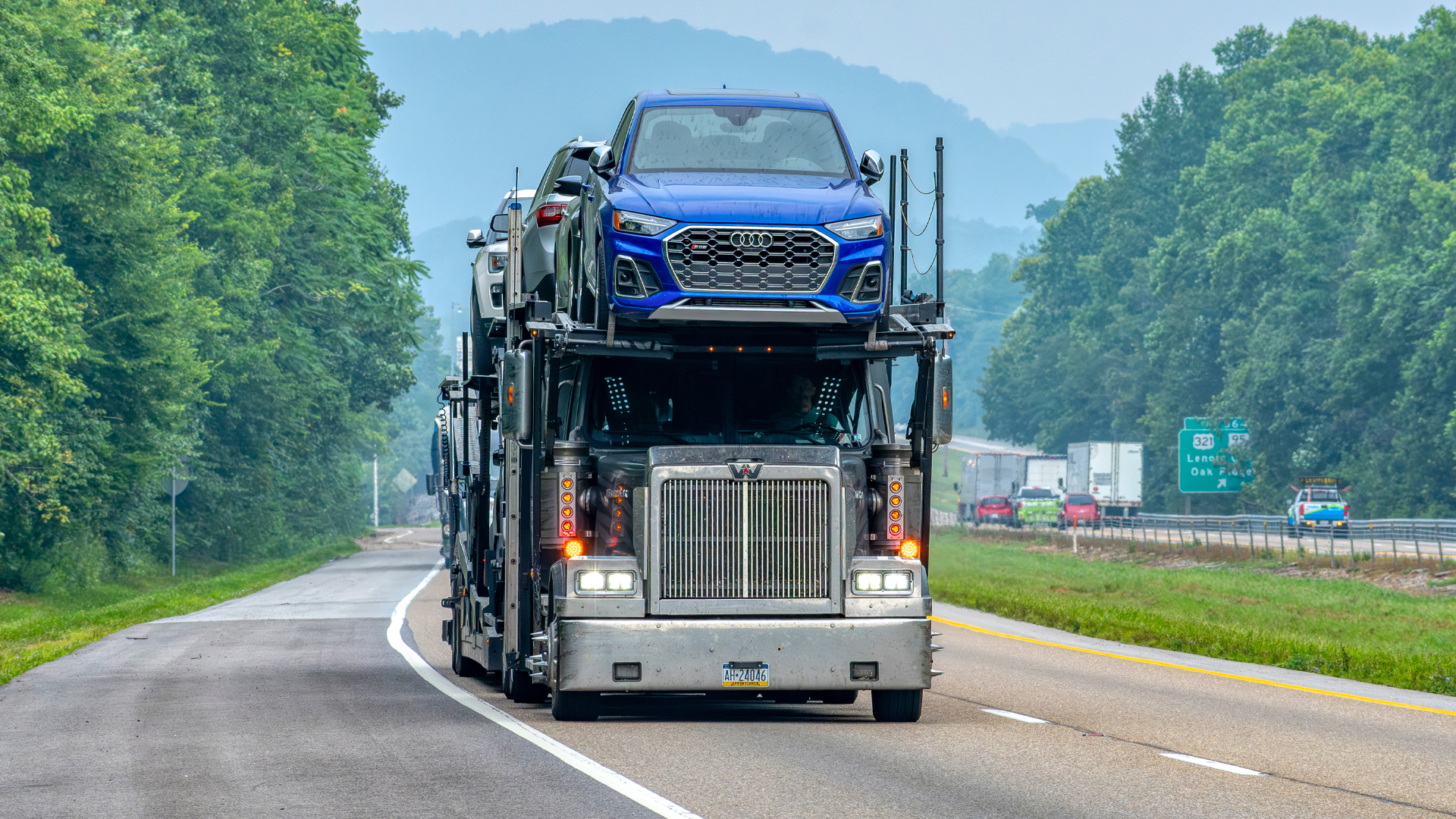 Audi being transported on top of a semi-truck car carrier.