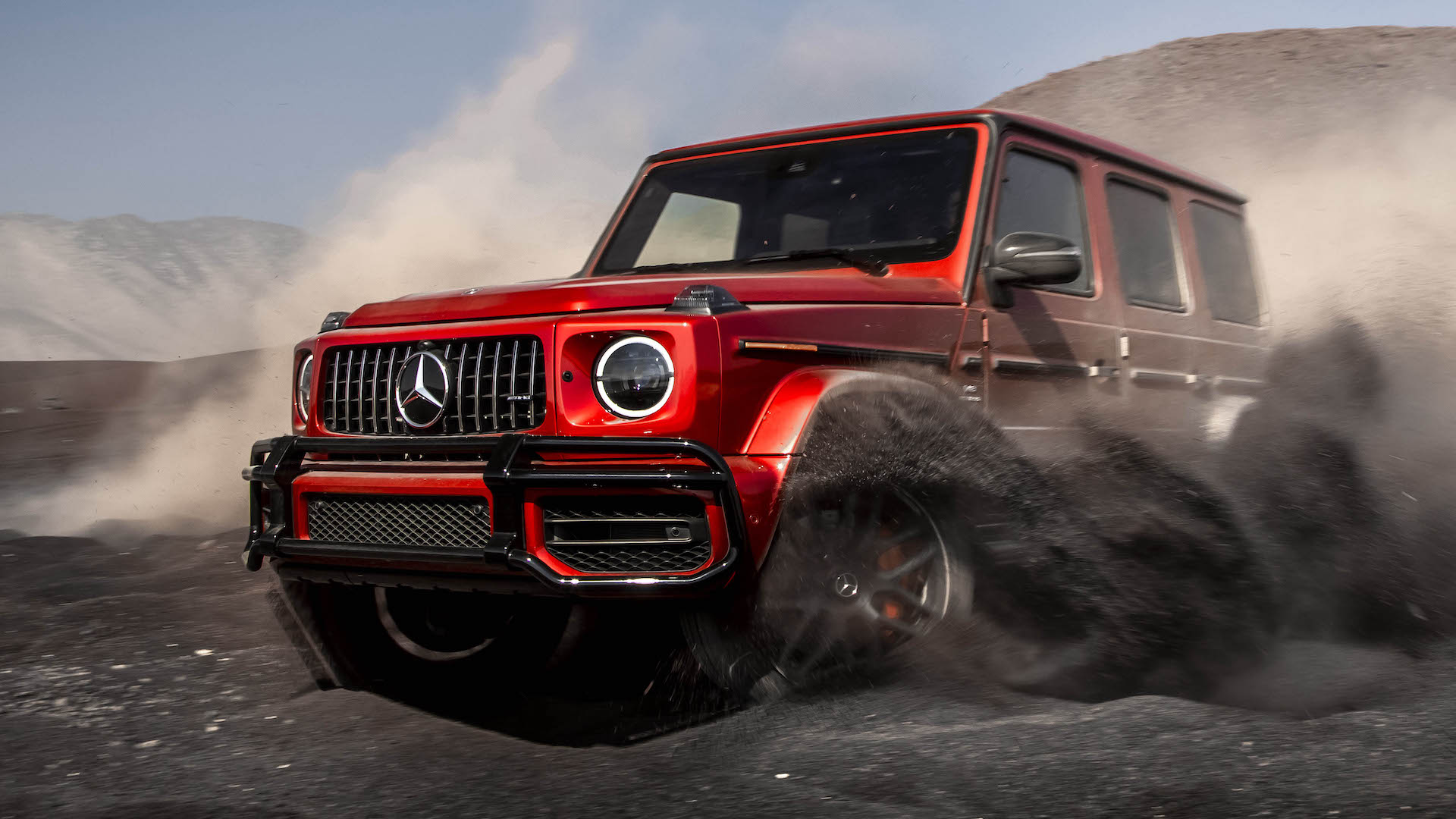 A red Mercedes-AMG G63 throws up clouds of dirt
