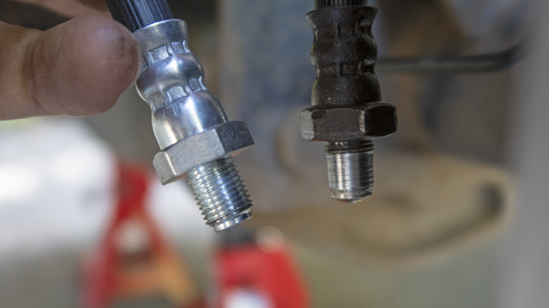 Two automotive brake hoses, one stripped of threads.