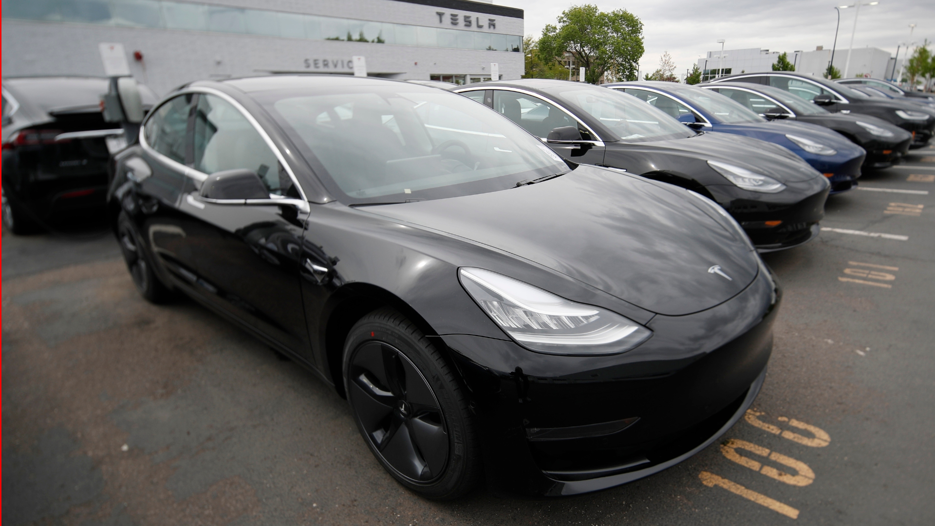 Teslas in parking lot outside dealership-like building.